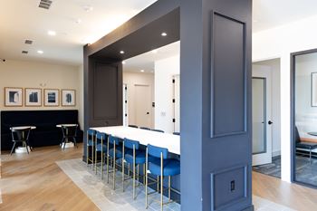 A long dark blue hallway with a row of blue chairs on one side.